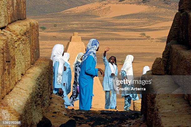 Young women dressed in tobes and hijabs visiting the Pyramids of Meroe in the Sahara desert, Sudan, North Africa.
