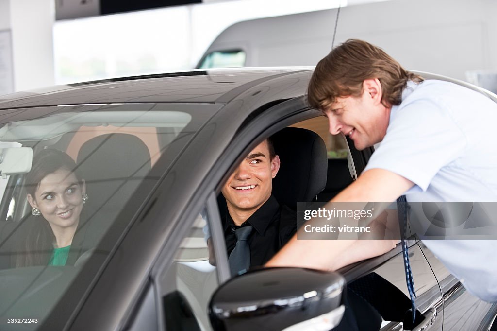 Car salesperson showing customers a new car