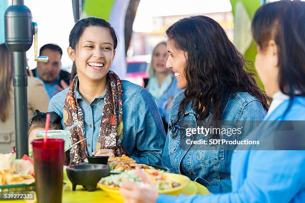 happy young hispanic woman having dinner in restaurant with family - mexican restaurant stock pictures, royalty-free photos & images