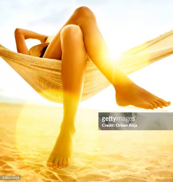 femme se détendre dans un hamac sur la plage - couché de soleil photos et images de collection