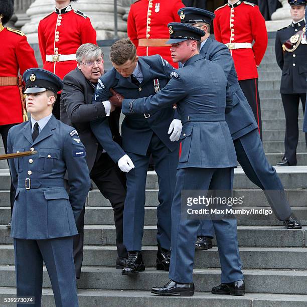 An RAF Airman forming part of the guard of honour is helped to his feet after collapsing at a national service of thanksgiving to mark Queen...