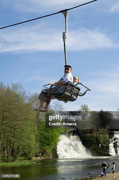 Tourists in chair lift above the river Ambleve in front of the waterfalls of Coo, Stavelot, Belgian Ardennes, Belgium.