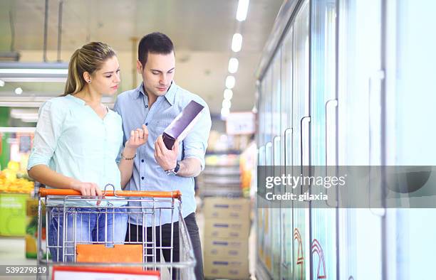 couple buying frozen food in supermarket. - nutrition label stock pictures, royalty-free photos & images