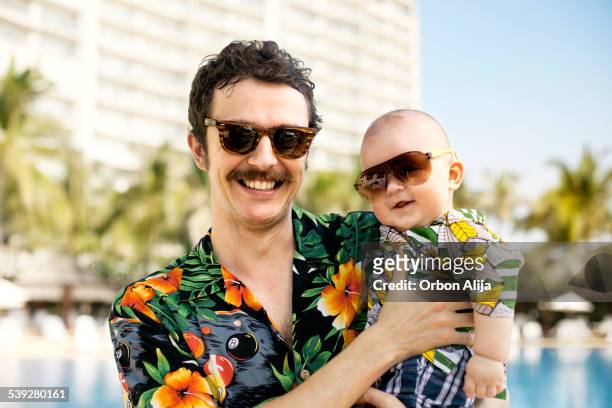 father and his son with hawaian shirts - baby in sunglass stockfoto's en -beelden
