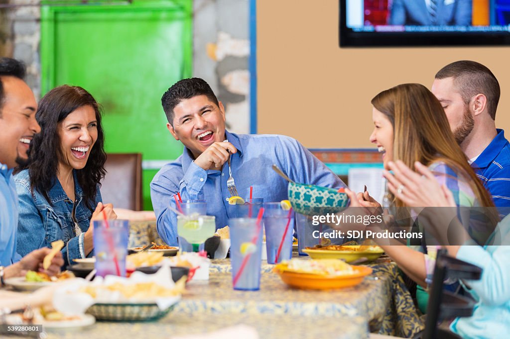 Large group of friends laughing during dinner in Tex-Mex restaurant