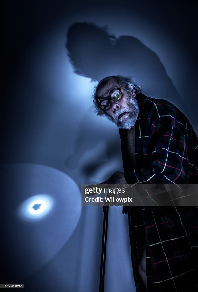Scared Senior Man in Dark Room With Flashlight