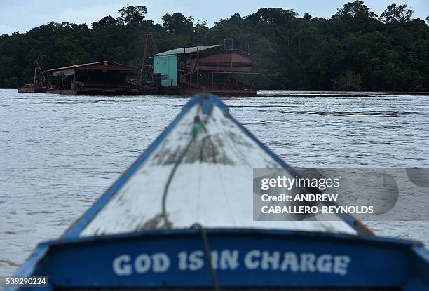 River boat moves towards a gold mining barge on the Mazaruni river near the town of Bartica, Guyana on June 6, 2016. Bartica is a town at the...