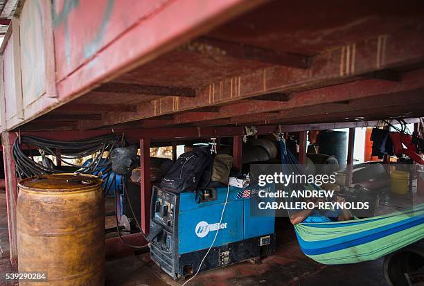 Guyanese indigenous gold miner rests in a hammock near a generator on a river mining barge near the town of Bartica, Guyana on June 6, 2016. Bartica...