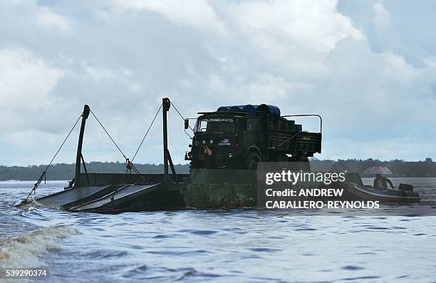 Gold mining truck is pushed down the Mazaruni river by a smaller river boat near the town of Bartica, Guyana on June 6, 2016. Bartica is a town at...