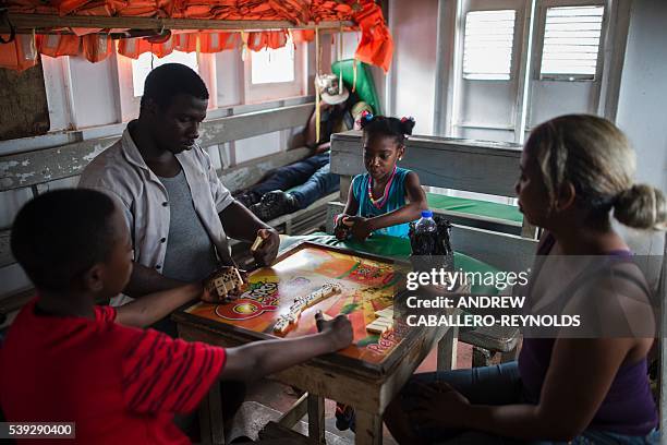 Family waiting to go upriver deeper into the interior plays dominoes on a boat docked in the town of Bartica, Guyana on June 6, 2016. Bartica is a...