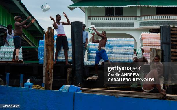 Group of men unload water from a boat in the town of Bartica, Guyana on June 6, 2016. Bartica is a town at the confluence of two major rivers and is...