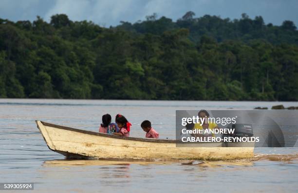 Woman brings children home from school on a boat near the town of Bartica, Guyana on June 6, 2016. Bartica is a town at the confluence of two major...