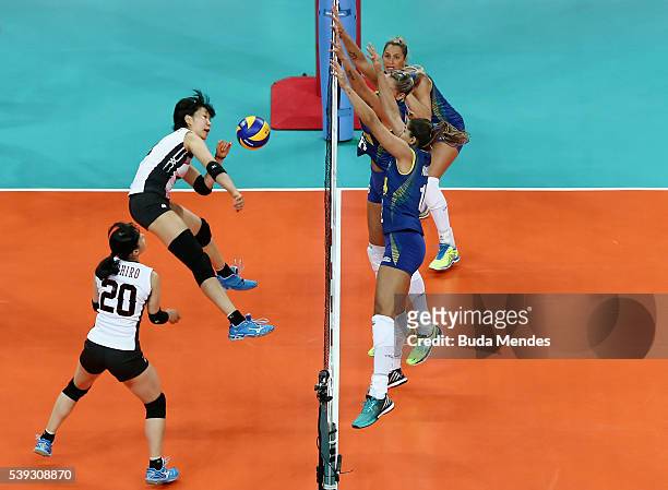 Sarina Koga of Japan spikes the ball as Thaisa Menezes and Natalia Pereira of Brazil defend during the match between Brazil and Japan on day 2 the...