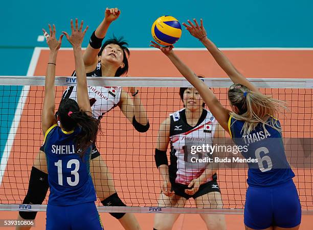 Riho Otake of Japan spikes the ball as Thaisa Menezes and Sheila Castro of Brazil defend during the match between Brazil and Japan on day 2 the FIVB...