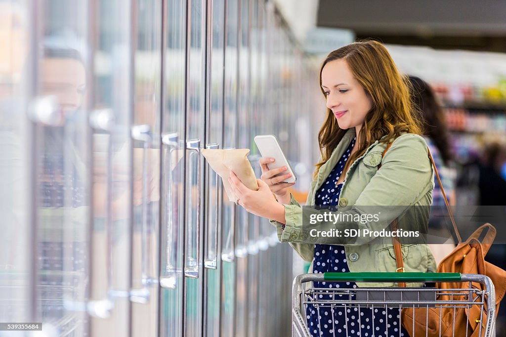 Frau benutzt Telefon im Supermarkt