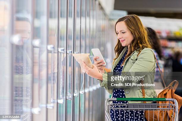 woman using phone at grocery store - happy customer grocery stock pictures, royalty-free photos & images
