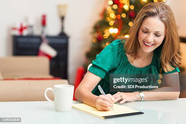 pretty woman writing letter at christmas - christmas list stock pictures, royalty-free photos & images