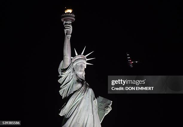 The Solar Impulse 2 aircraft flies over the Statue of Liberty before landing at JFK airport June 11, 2016 in New York. Solar Impulse 2 landed in New...