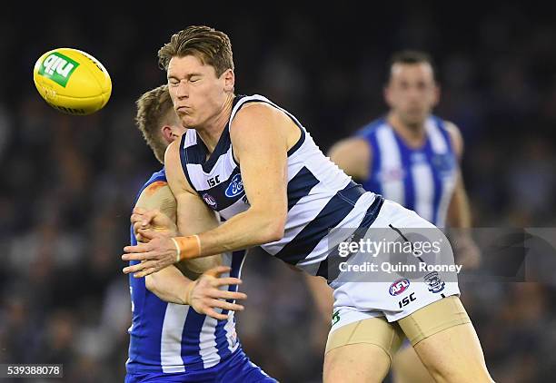 Mark Blicavs of the Cats handballs whilst being tackled by Jack Ziebell of the Kangaroos during the round 12 AFL match between the Geelong Cats and...