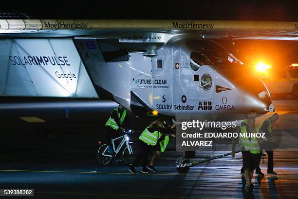 Team members of The Solar Impulse 2 aircraft push the plane after being successfully landed by Swiss pilot Andre Borschberg at JFK International...