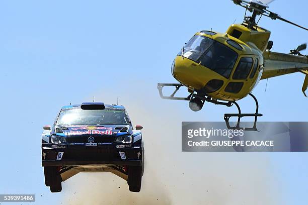 Finnish driver Jari Matti Latvala and Finish co-driver Miikka Anttila jump next to helicopter as the drive their Volkswagen Polo R WRC near Pattada,...