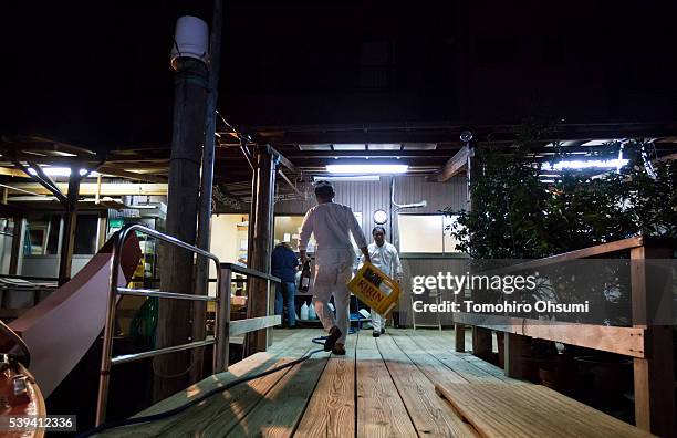 Employees walk on the pier for the yakatabune, or traditional low barge style boat, at Mikawaya shipping agent after finishing their shift on June...