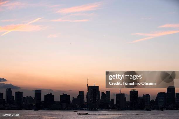 Yakatabune, or traditional low barge style boat, sails past commercial buildings in Tokyo Bay at dusk on June 10, 2016 in Tokyo, Japan. About 35...