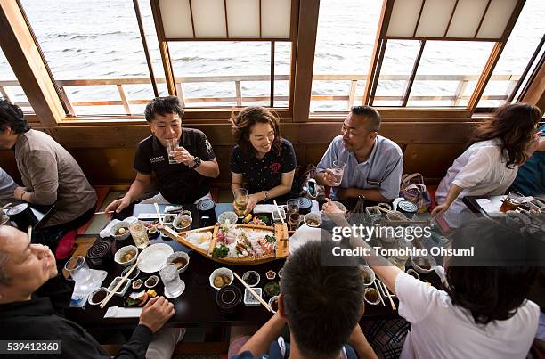 Customers ride on a yakatabune, or traditional low barge style boat, operated by Mikawaya shipping agent, as it sails through Tokyo Bay on June 11,...