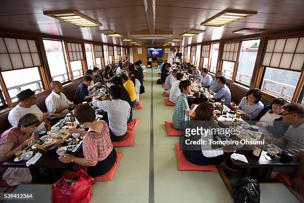 Customers ride on a yakatabune, or traditional low barge style boat, operated by Mikawaya shipping agent, as it sails through Tokyo Bay on June 11,...