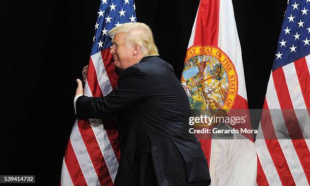 Republican presidential candidate Donald Trump embraces the United States flag during a campaign rally at the Tampa Convention Center on June 11,...