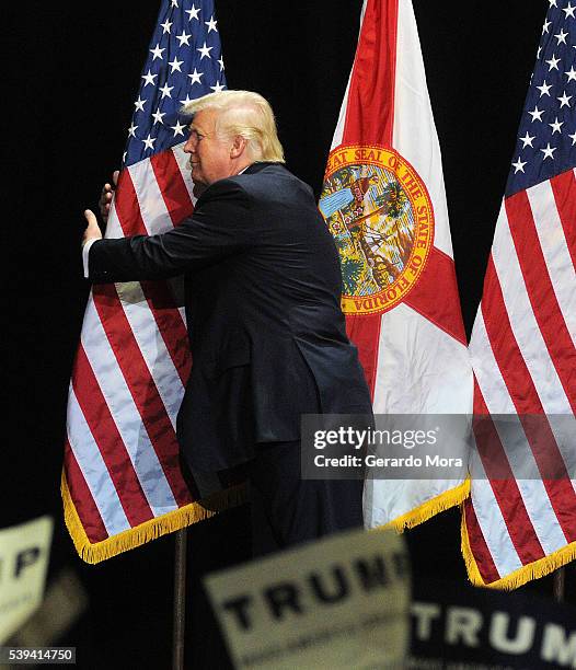 Republican presidential candidate Donald Trump embraces the United States flag during a campaign rally at the Tampa Convention Center on June 11,...