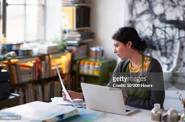 Young female artist in studio working on laptop