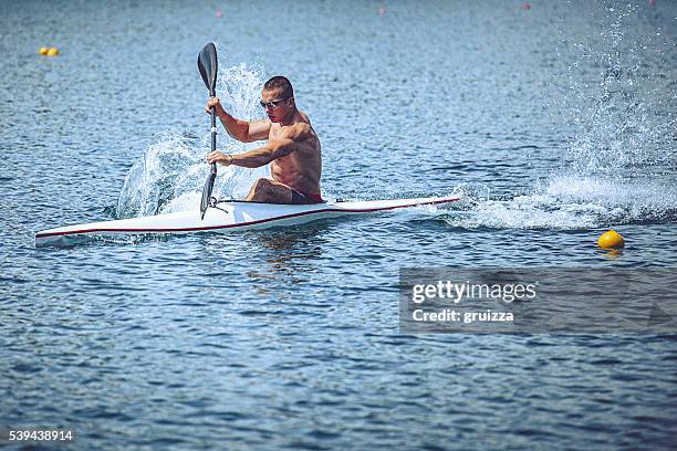 joven hombre muscular en sprint kayak capacitación en agua. - canoa fotografías e imágenes de stock