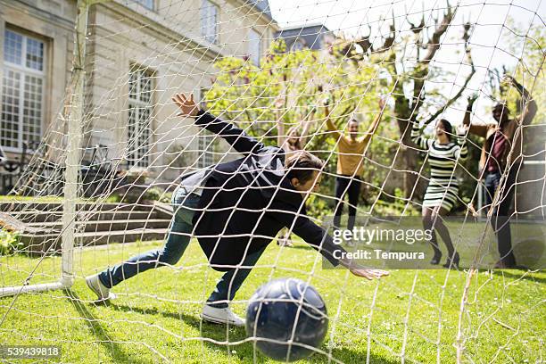 group of friends enjoying time in a garden playing football - celebrates exclusive sport cooperation stock pictures, royalty-free photos & images