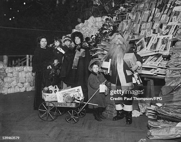 Santa Claus visits the 9th Regiment Armory on 14th Street, New York City, to distribute toys to children, circa 1910. Evangeline Booth , Commander of...