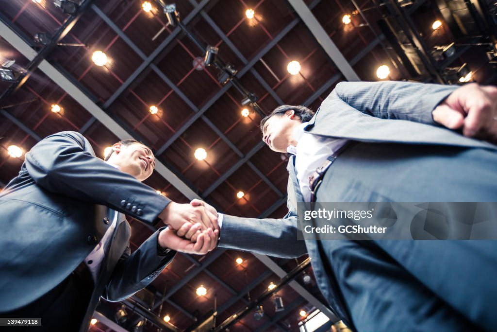 Businessmen shaking hands in agreement over a successful acquisition.