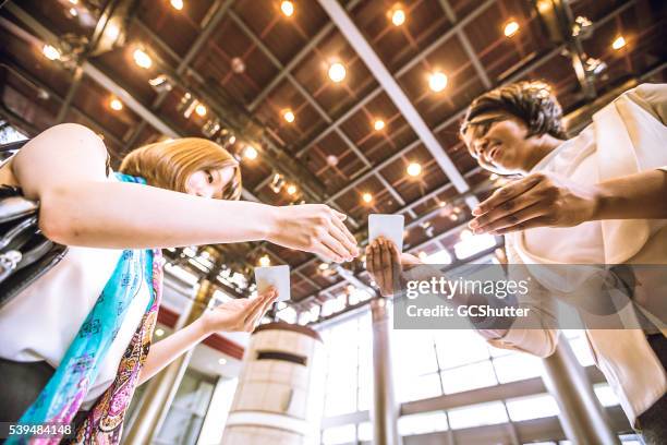 mujeres jóvenes empresarios el intercambio de tarjetas de visita - tarjeta de negocios fotografías e imágenes de stock