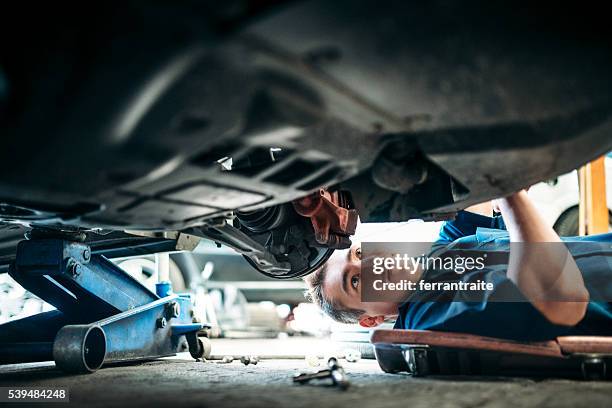 auto-mechaniker arbeiten unter dem auto - werkstatt stock-fotos und bilder