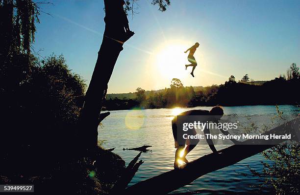 Young men jump from a tarzan swing into the Nepean River at Penrith during record high temperatures, 13 October 2004. SMH NEWS Picture by ADAM...