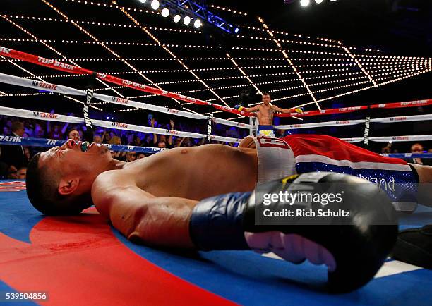 Roman Martinez is knocked out as Vasyl Lomachenko raises his arms in the neutral corner during the fifth round of their Junior Lightweight WBO World...