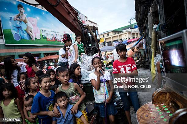 In this picture taken on June 8 children sing karaoke along a street in Divisoria market in Manila. Since winning the presidential election Rodrigo...