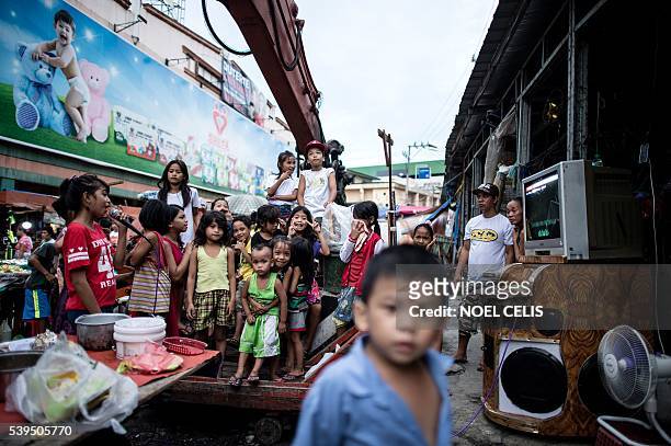 In this picture taken on June 8 children sing karaoke along a street in Divisoria market in Manila. Since winning the presidential election Rodrigo...