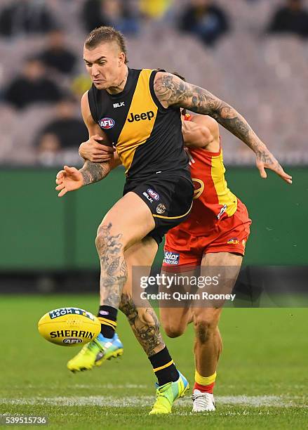 Dustin Martin of the Tigers kicks whilst being tackled by Jesse Lonergan of the Suns during the round 12 AFL match between the Richmond Tigers and...