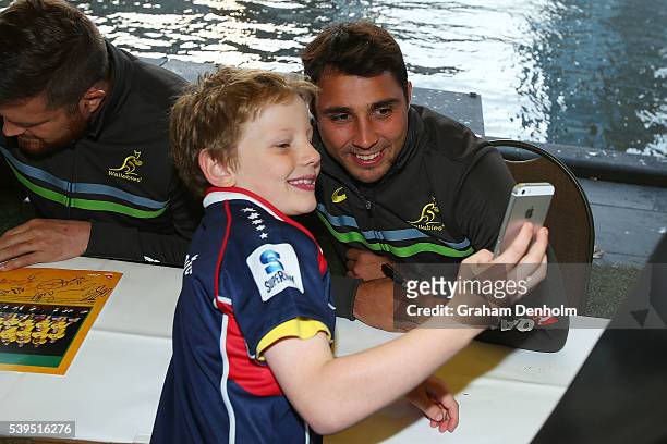 Nick Phipps of the Wallabies poses for a photograph with a young fan during the Australian Wallabies Fan Day at The Crown Promenade River Walk on...