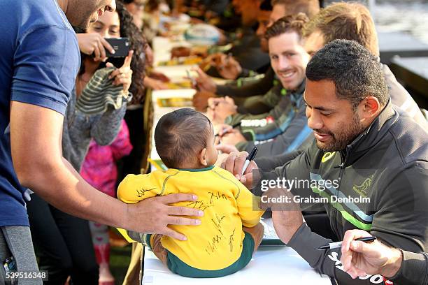 Tatafu Polota-Nau of the Wallabies signs his autograph for a young fan during the Australian Wallabies Fan Day at The Crown Promenade River Walk on...