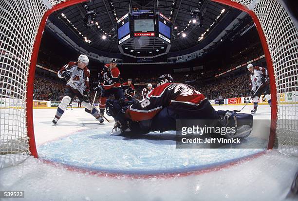 Alex Tanguay of the Colorado Avalanche trys to shoot the puck as he is blocked by Scott Lachance of the Vancouver Canucks and Goalkeeper Dan Cloutier...