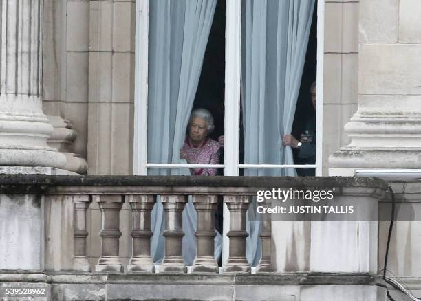 Britain's Queen Elizabeth II looks out from Buckingham Palace as guests gather for the Patron's Lunch, a street party to be held along the Mall in...