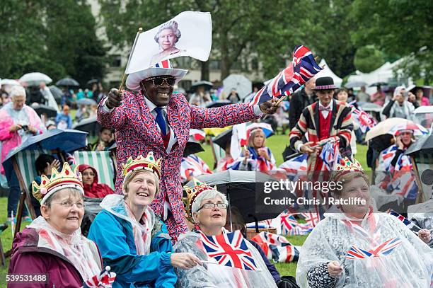 Joseph Afrane in Union Jack clothing waves flags as members of the public in Green Park gather for a picnic and watch The Queen's Patronage on a big...