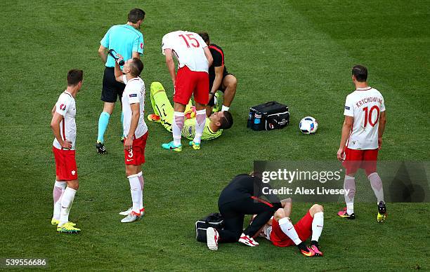 Wojciech Szczesny and Lukasz Piszczek of Poland receive medical treatment after their collision during the UEFA EURO 2016 Group C match between...