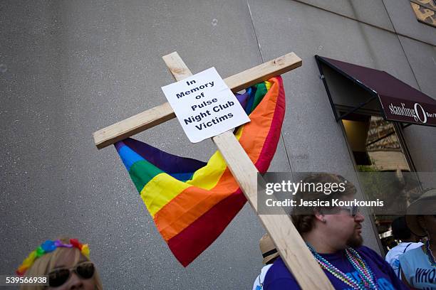 Austin Ellis, a member of Metropolitan Community Church, carries a cross with a sign in memory of the victims of the Pulse nightclub shooting as he...